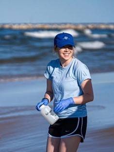Lexy Porter collecting a water sample from a Lake Michigan beach.